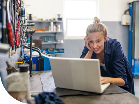 person smiling in a workshop at laptop